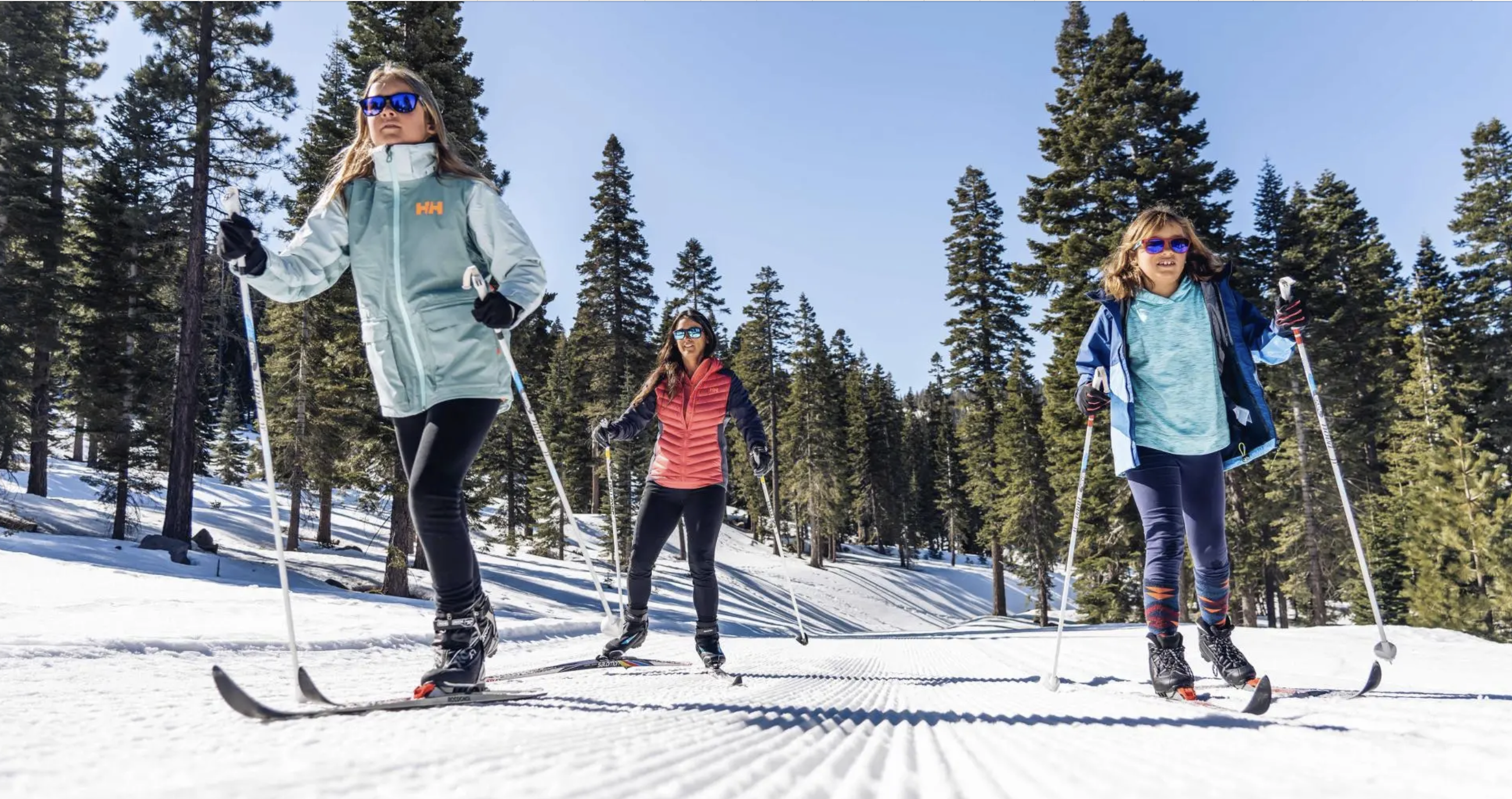 Cross-country skiers on groomed trails through pine forests near Truckee