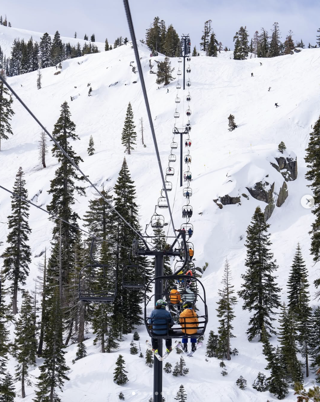 Skiers on the slopes at Palisades Tahoe with mountain views